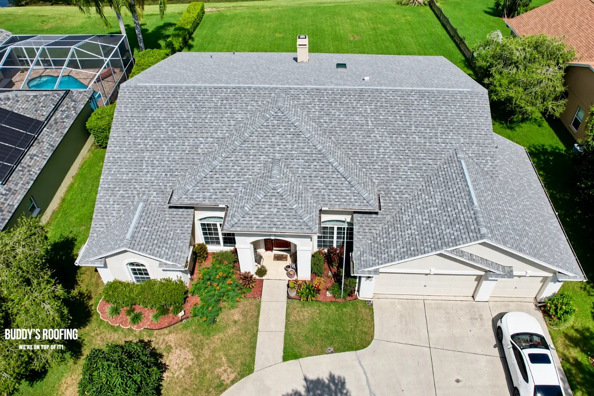 A roofer inspecting the trouble spot on a residential roofing job, crouched close to the work with a nail gun and chalk line in hand, natural side light raking across the surface