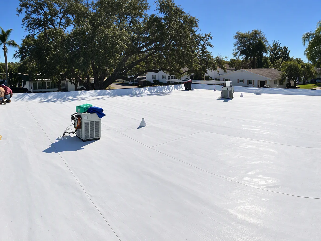 A roofer working on a residential tpo roofing job — mid-task, hands, tools and the work itself in sharp focus, the rest of the space softly out of focus